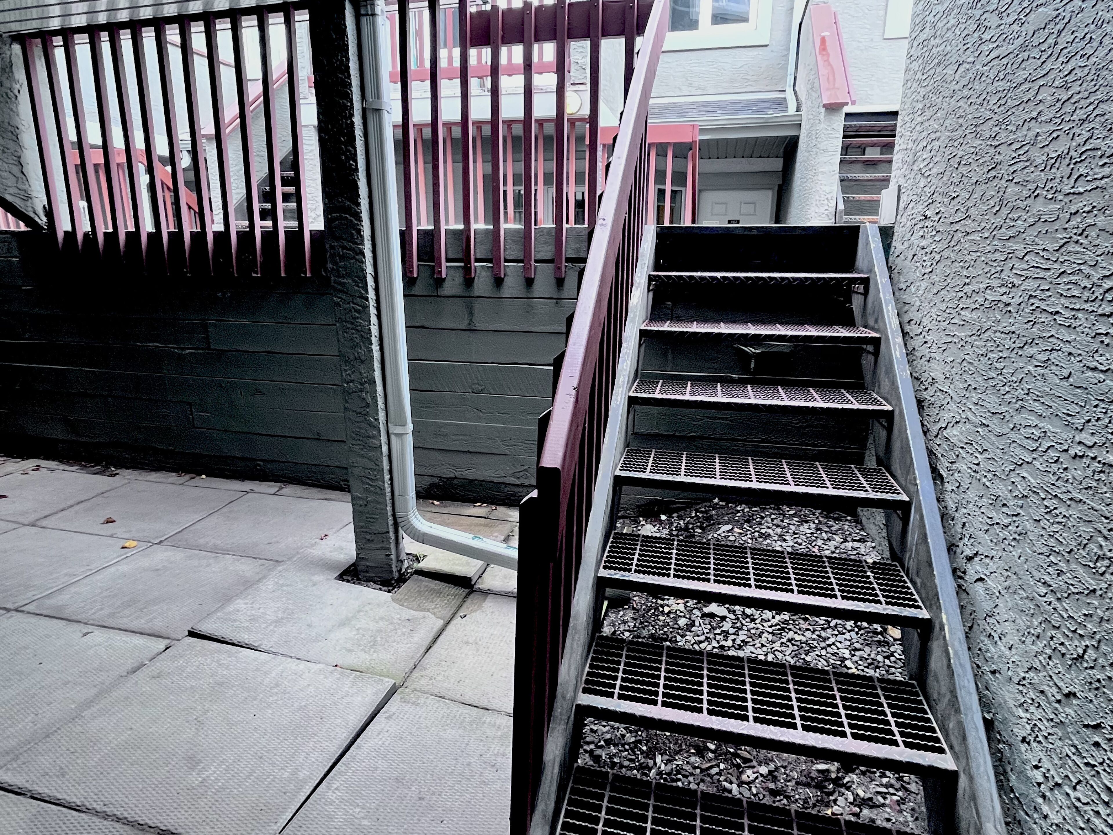Eine Metalltreppe mit Metallgeländer führt zu einem Hauseingang.
