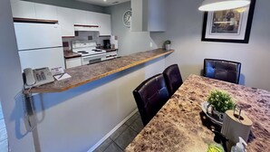Une cuisine moderne avec des armoires blanches, une cuisinière encastrée et un plan de travail sur lequel se trouvent un téléphone et une machine à café.