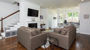 A modern living room with a fireplace, two sofas, a coffee table, and a TV mounted on the wall.