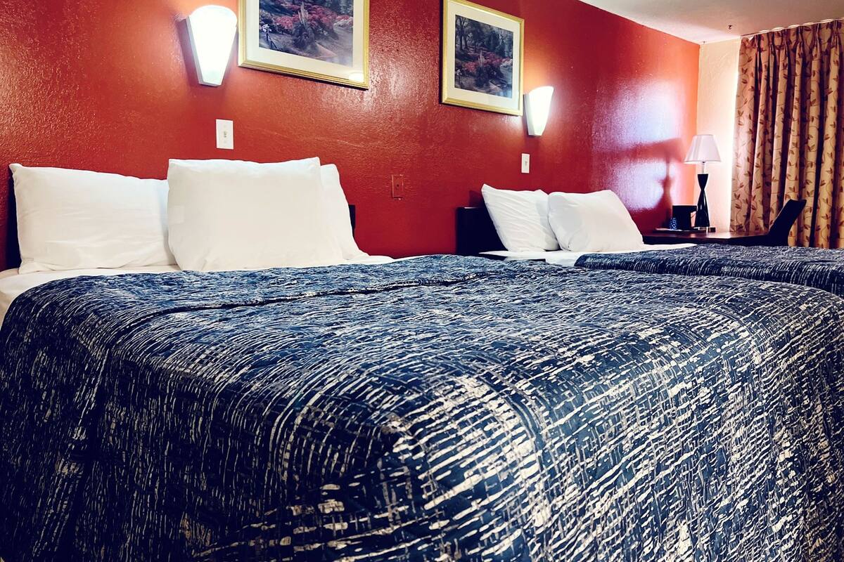 A hotel room with a large bed, two wall-mounted lamps, and two framed pictures on the wall.