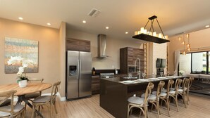 A modern kitchen with a central island, stainless steel appliances, and a dining area with wooden chairs. - Resort Style Home Near Disney, Wi-Fi & Parking, BBQ Grill Shared Heated Pool (Kissimmee)
