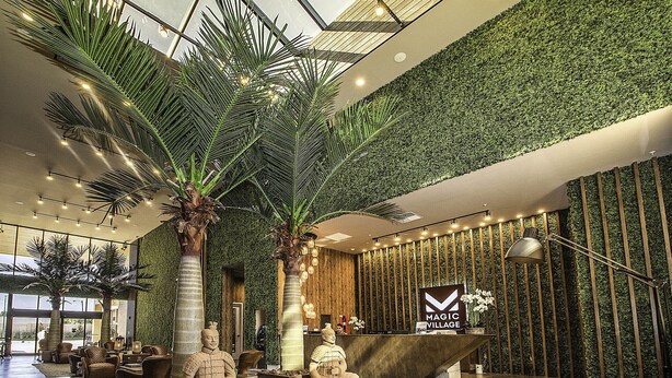 A lobby with a reception desk, palm trees, and a green wall. - Resort Style Home Near Disney, Wi-Fi & Parking, BBQ Grill Shared Heated Pool (Kissimmee)