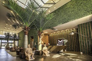 A lobby with a reception desk, palm trees, and a green wall. - Resort Style Home Near Disney, Wi-Fi & Parking, BBQ Grill Shared Heated Pool (Kissimmee)