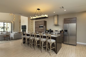 A modern kitchen with a central island, stainless steel appliances, and a dining area with chairs and a table.