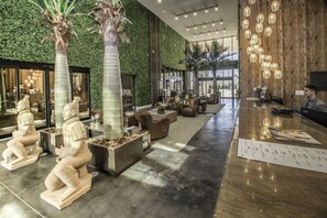 A modern lobby with a green wall, seating areas, and a reception desk.
