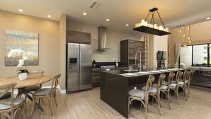 Una cocina moderna con una isla central, electrodomésticos de acero inoxidable y un comedor con sillas de madera.