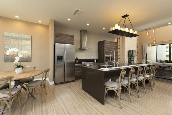 A modern kitchen with a central island, stainless steel appliances, and a dining area with wooden chairs.