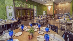 Ein Restaurant mit runden Tischen, gedeckt mit blauem Glas und weißen Tellern.