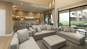 A spacious living area with multiple sofas and a coffee table, large windows with a view of greenery, and a modern chandelier. - 5 Miles to Disney/Gorgeous Home/Wi-Fi/Parking/BBQ Grill/Family Friendly (Kissimmee)