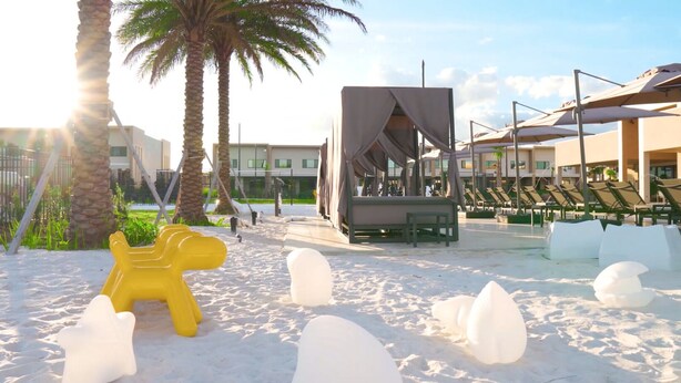 A beach area with a yellow sculpture, white ice sculptures, palm trees, and a covered seating area with umbrellas. - 5 Miles to Disney/Gorgeous Home/Wi-Fi/Parking/BBQ Grill/Family Friendly (Kissimmee)