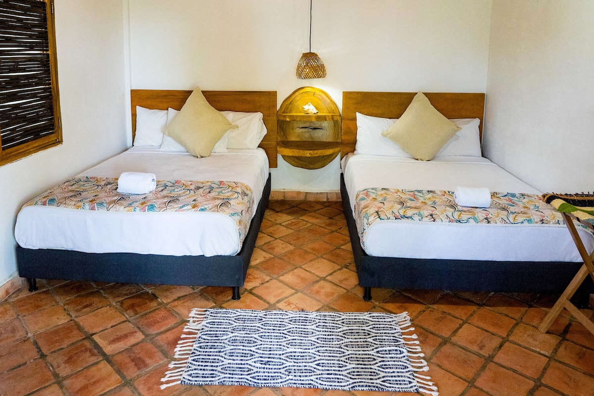 A room with two beds, a ceiling fan, and a tiled floor.