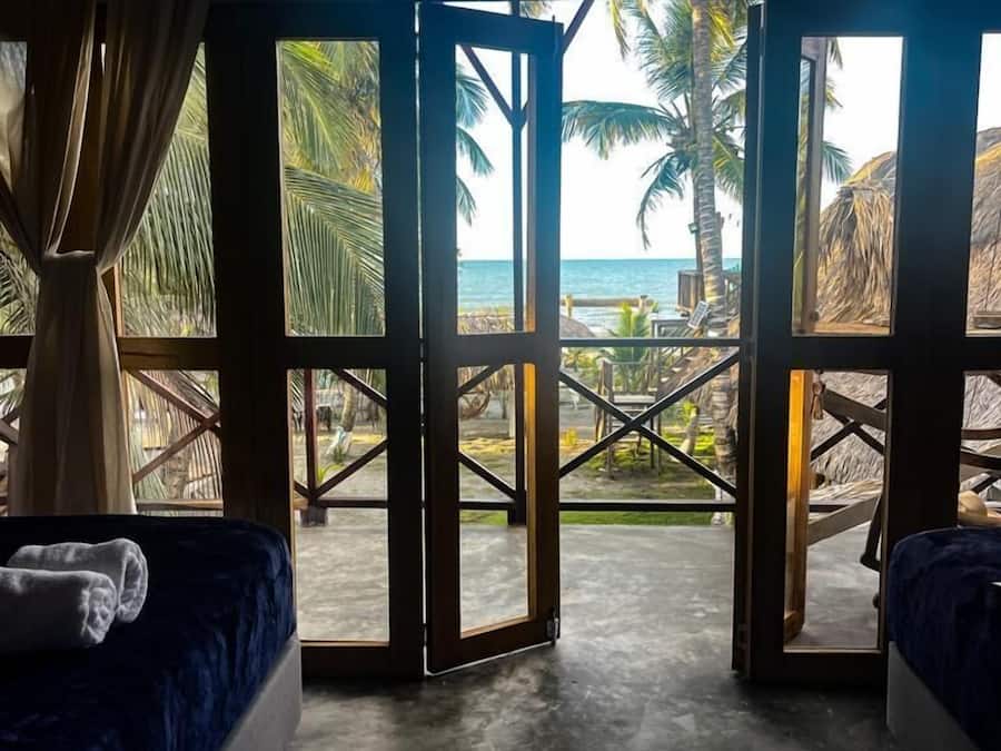 Habitación con vistas a la playa, con dos camas, un amplio ventanal y suelo de hormigón.