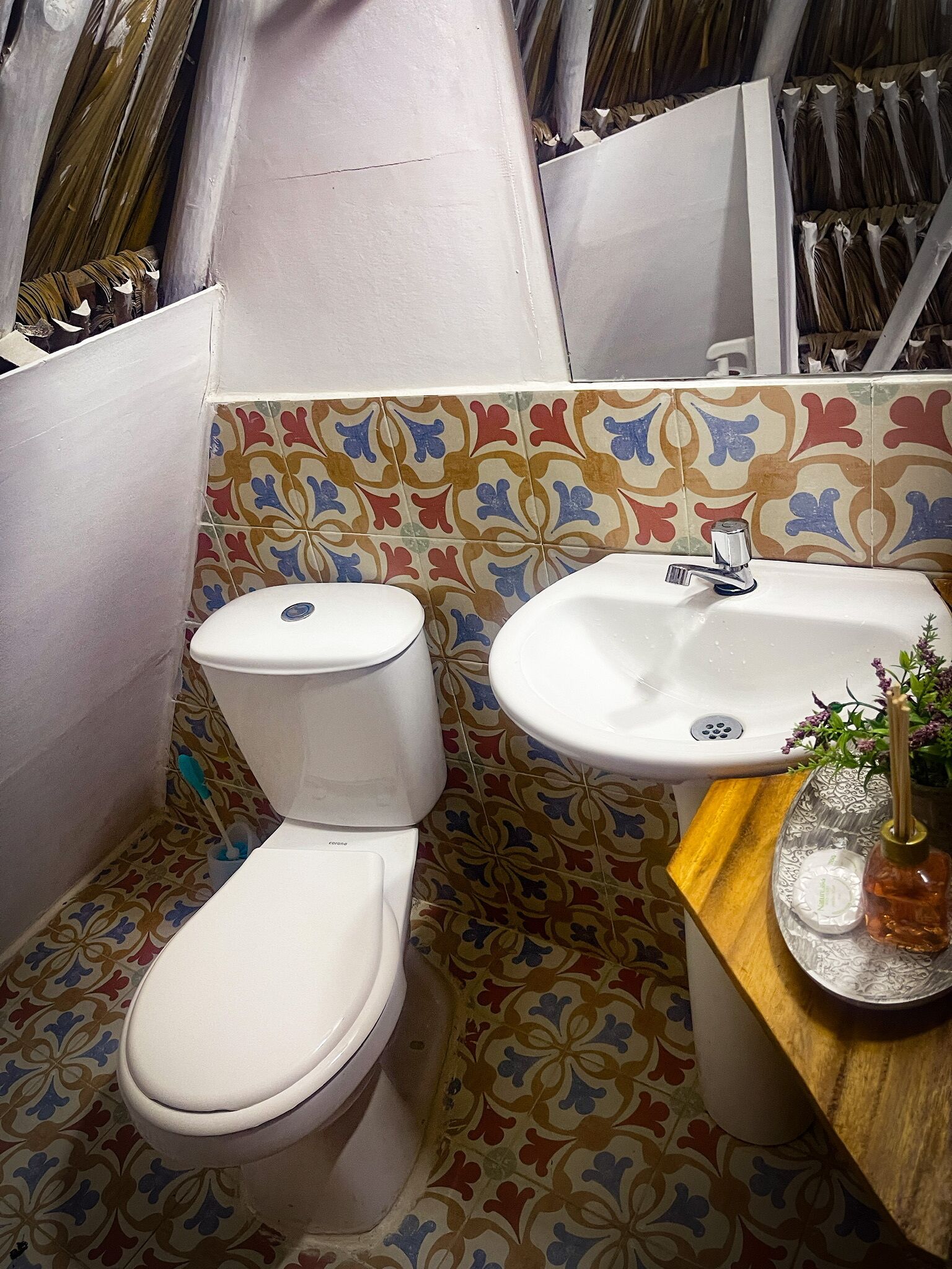 A bathroom with a toilet, sink, and decorative tiles.