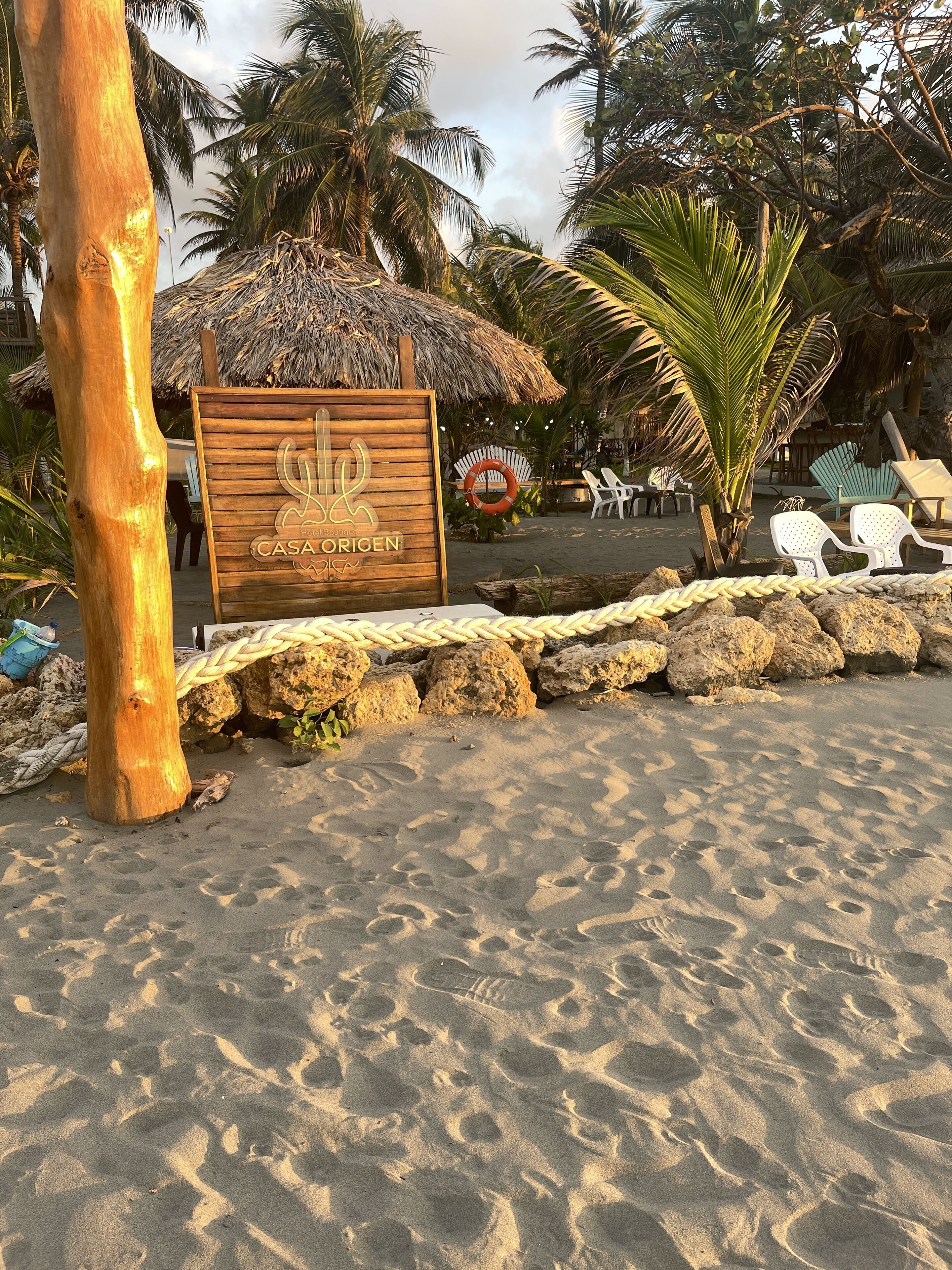 A wooden sign with "CASA ORIGEN" and a palm tree.