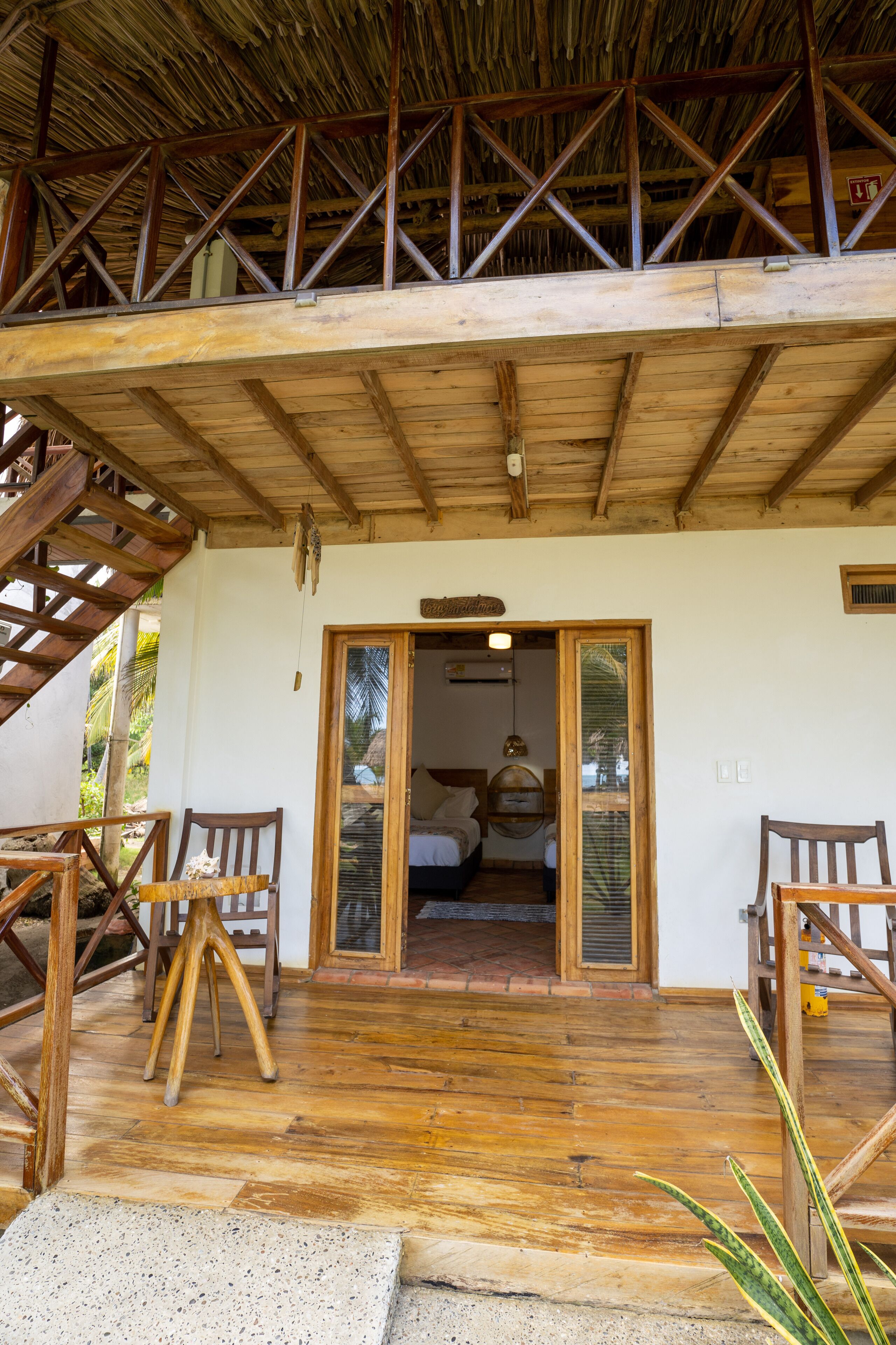 Eine Holzterrasse mit einer Treppe, die zu einem Zimmer mit einem Bett und einem kleinen Tisch führt.