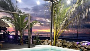 A swimming pool with a tiled floor, surrounded by palm trees and a sunset view. - CASA ORIGEN BOUTIQUE (San Bernardo del Viento)