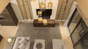 A modern living room with a sectional sofa, a coffee table, and a TV on a wooden stand. There are two ladders against the wall, a fireplace, and a large window with curtains. - Welcome Home! 4Beds/4.5 Baths, Entire House near Disney, Free Parking & Wi-Fi, (Kissimmee)