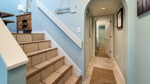 A staircase with beige steps and white handrails, leading to a landing with a 'WELCOME' sign.