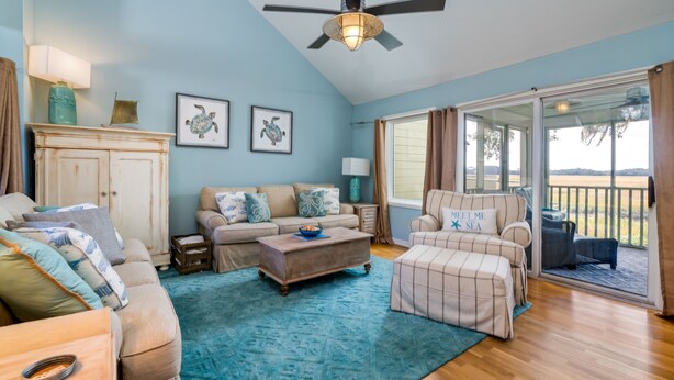 A spacious living room with a large window, a ceiling fan, and a view of the outdoors.