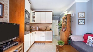 A compact living space with a kitchenette, a flat-screen TV, a sofa, and a wooden cabinet. - Home2Book CrisSol Los Cristianos Pool Retreat (Los Cristianos)