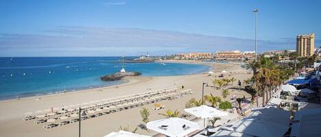 A beach resort with sun umbrellas, a sandy beach, and a view of the ocean.