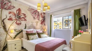 A bedroom with a bed, nightstand, dresser, and a large window with curtains. - Home2Book CrisSol Los Cristianos Pool Retreat (Los Cristianos)