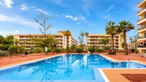 A swimming pool with a tiled deck, surrounded by palm trees and a multi-story building with balconies. - Home2Book CrisSol Los Cristianos Pool Retreat (Los Cristianos)
