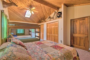 A bedroom with a wooden ceiling, a large bed with a floral quilt, and a wooden door. - Idyllic Mt Sterling Retreat w/ Private Lake! (Mt. Sterling)