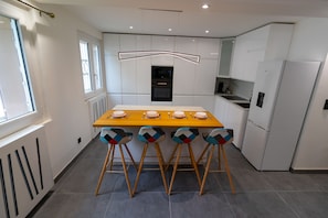 Una cocina moderna con una isla central, armarios blancos y un horno empotrado.