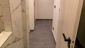 A hallway with marble walls and dark tiled flooring, leading to a room with a door. - *Free parking* Chic and elegant in VILLEURBANNE *All-inclusive* (Villeurbanne)