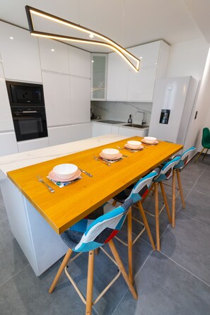 Una cocina moderna con una mesa de comedor de madera, armarios blancos y un horno empotrado.