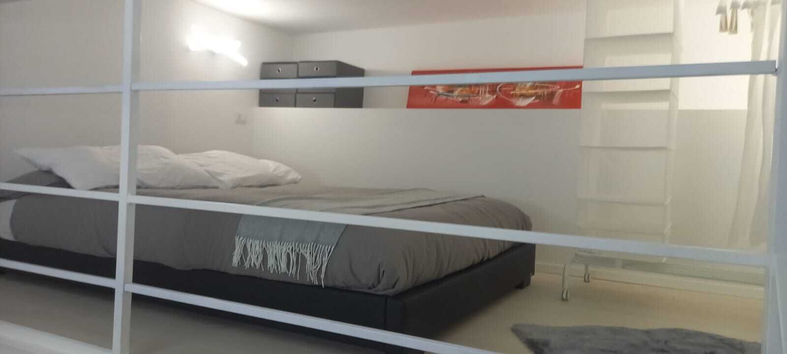Een slaapkamer met een bed, een kledingkast en een schilderij aan de muur.