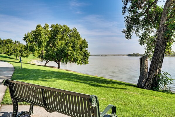 A park bench overlooking a lake with a tree and grassy area.