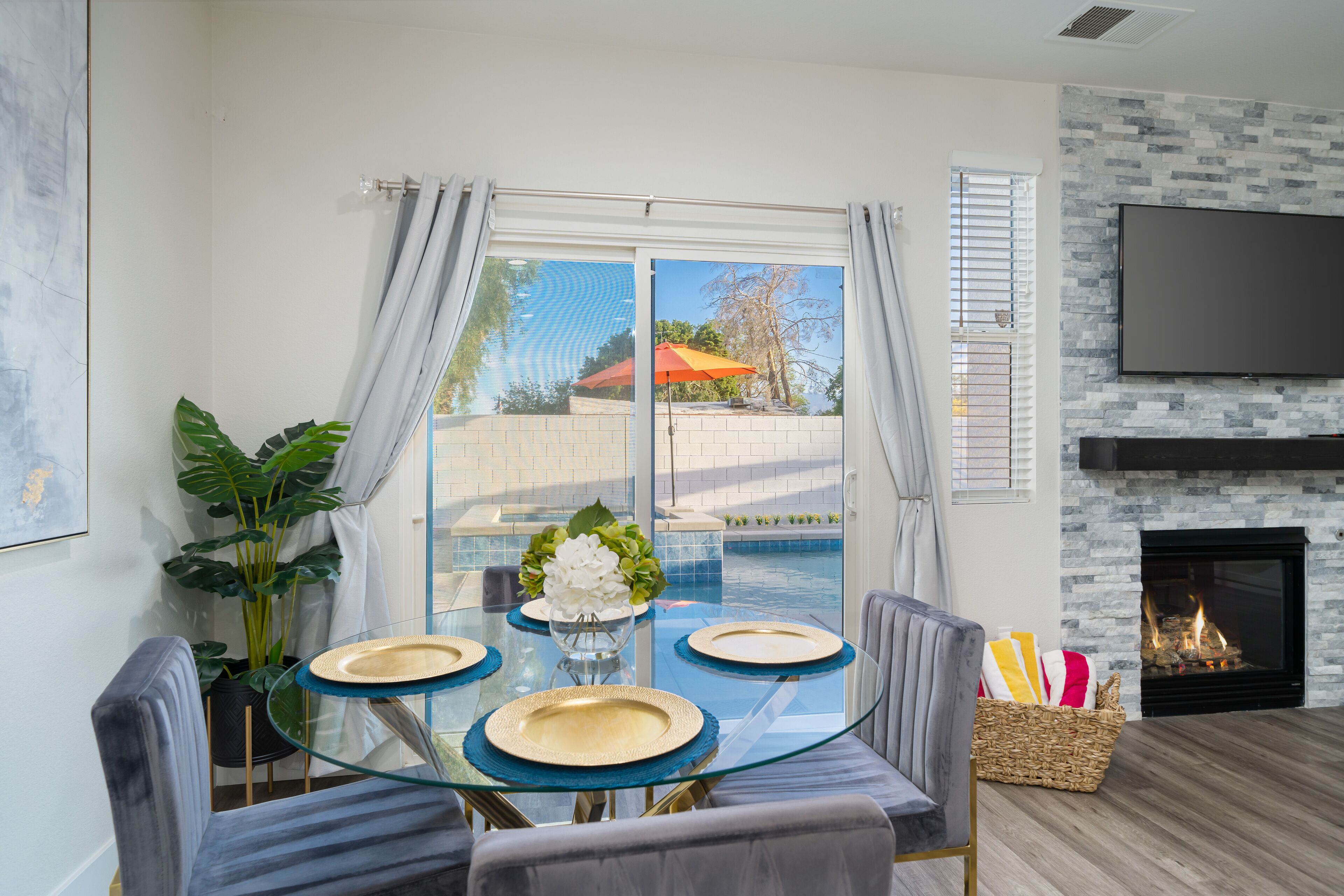 Un espace repas avec une table en verre, des chaises et une vue sur une piscine et un parasol extérieur.