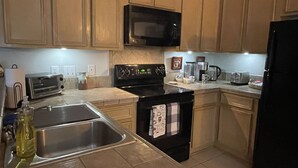 A kitchen with a stove, microwave, sink, and various appliances. - Lovely 1 bedroom apartment Pearland - Wi-Fi - Roku TV (Pearland)