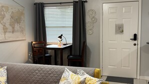 A cozy room with a quilted sofa, a small table with a lamp, a world map on the wall, and a door with a 'No Smoking Allowed' sign. - Lovely 1 bedroom apartment Pearland - Wi-Fi - Roku TV (Pearland)