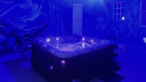 Ein Zimmer mit Whirlpool, Deckenventilator und Wandgemälde.