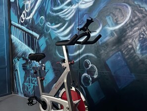 Una bicicleta estática en una habitación con un mural en la pared.