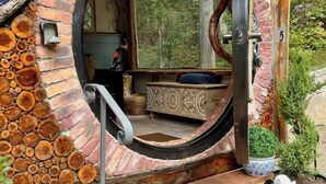 Un espace extérieur aménagé dans un style rustique, avec un mur circulaire en briques, un banc en bois et une rambarde en métal.