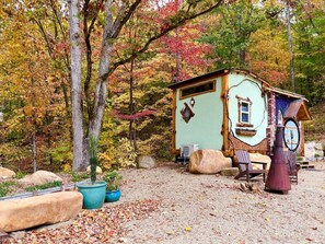 A rustic cabin with a chimney, surrounded by trees with autumn foliage.