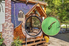 A Hobbit-style house with a round door, a small window, and a chimney.
