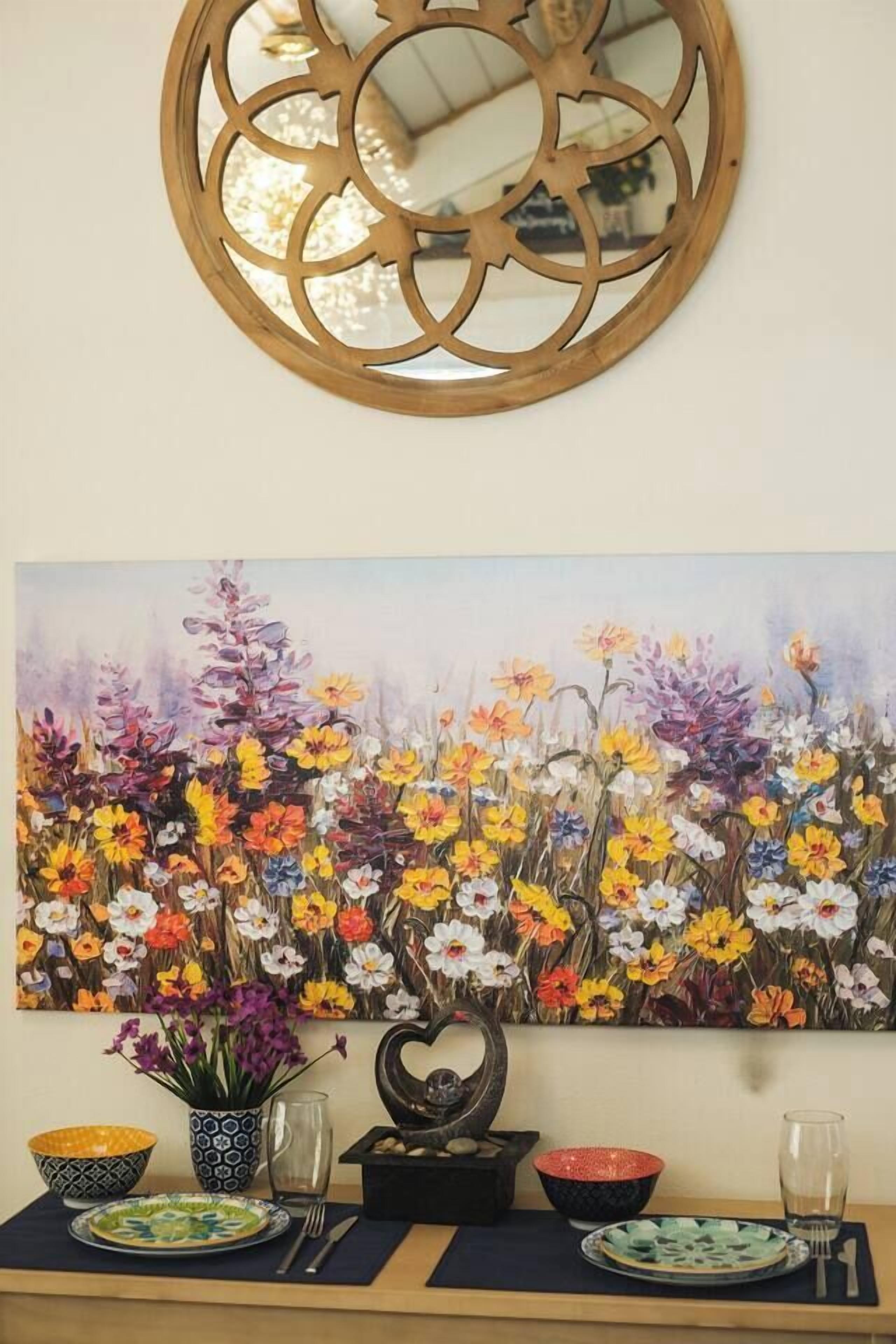 Ein Esstisch mit einem floralen Gemälde, einer Wanddekoration und einer Blumenvase.