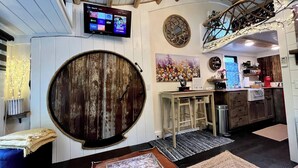 Ein rustikales Interieur mit einem Holzfass, einem an der Wand montierten Fernseher, einer Küchenzeile und einer Wanddekoration.