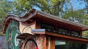 Eine rustikale Holzhütte mit einer markanten, gebogenen Tür, einer Holzfassade und einem kleinen Vorbereich.