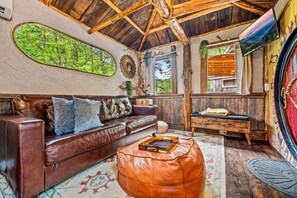Relax in this inviting space with a leather sofa, wooden bench, and natural views.