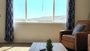 Ein Wohnzimmer mit Couchtisch aus Holz, einer Zimmerpflanze und einem braunen Ledersessel.