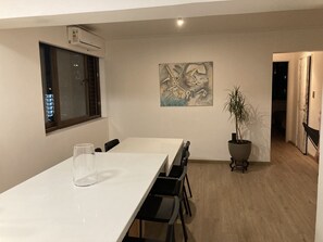 Ein moderner Essbereich mit einem weißen Tisch, schwarzen Stühlen, einer Topfpflanze und einem Gemälde an der Wand.