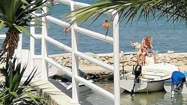 A coastal scene with a white dock, a small boat, and a person in the water. - Vacation apartment, quiet part. Perfect for your vacation! (Vir)