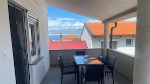 A balcony with a table and chairs, a view of buildings with red roofs, and a clear sky. - Vacation apartment, quiet part. Perfect for your vacation! (Vir)