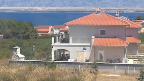 A coastal house with a red-tiled roof, a stone chimney, and a view of the sea and mountains in the background. - Vacation apartment, quiet part. Perfect for your vacation! (Vir)